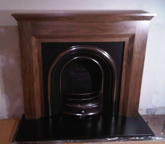 Simple walnut fire surround and cast iron fireplace
